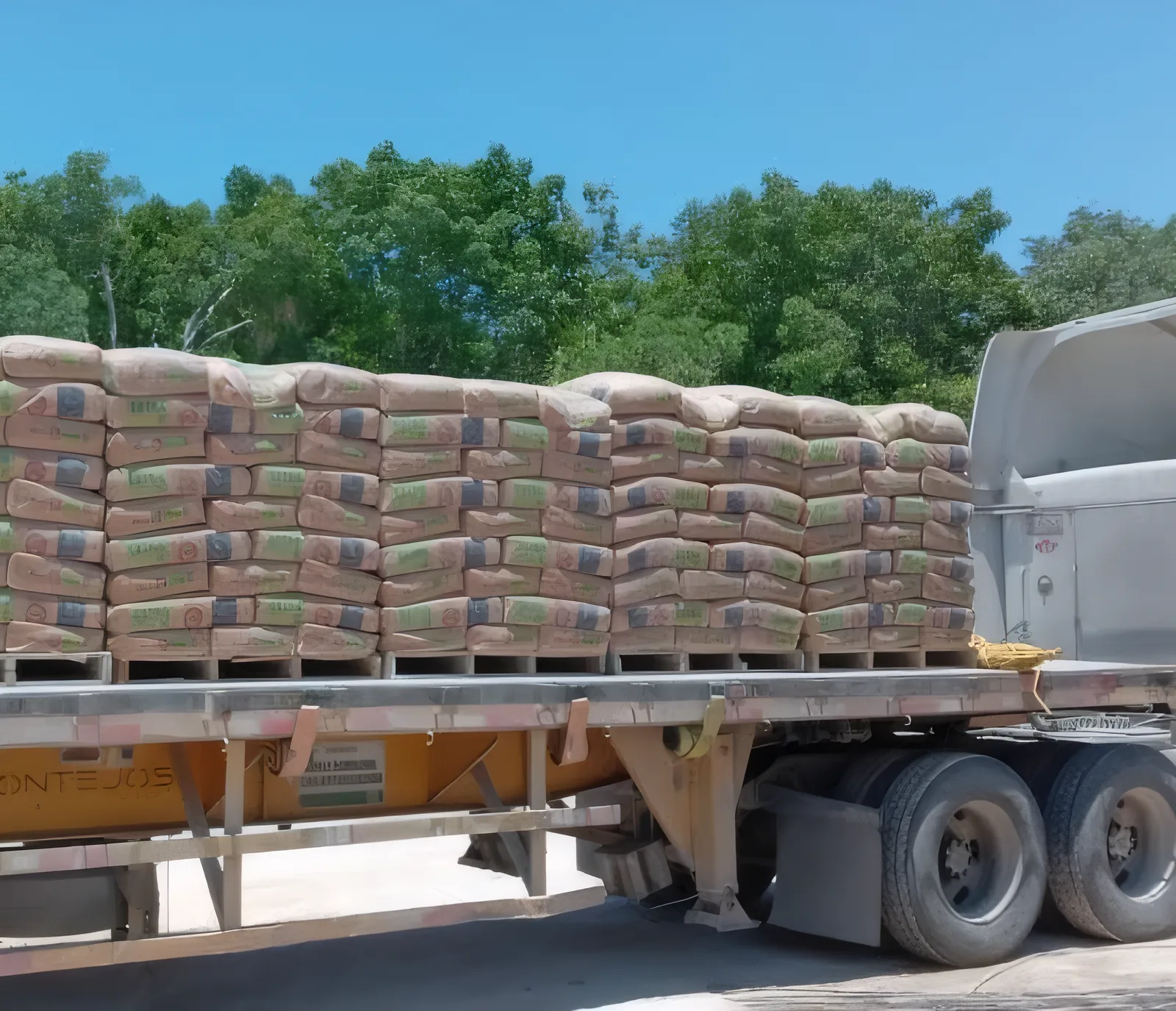 Camión de plataforma cargado con tarimas de sacos de cemento