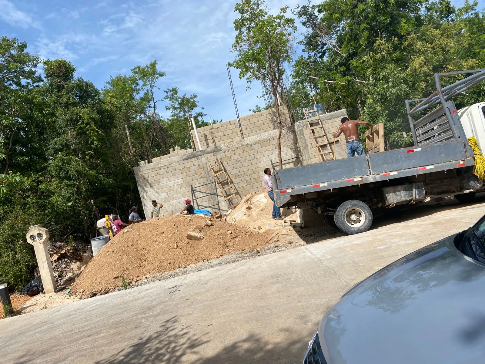 Camión de plataforma estacionado junto a un muro de block y un montón de tierra