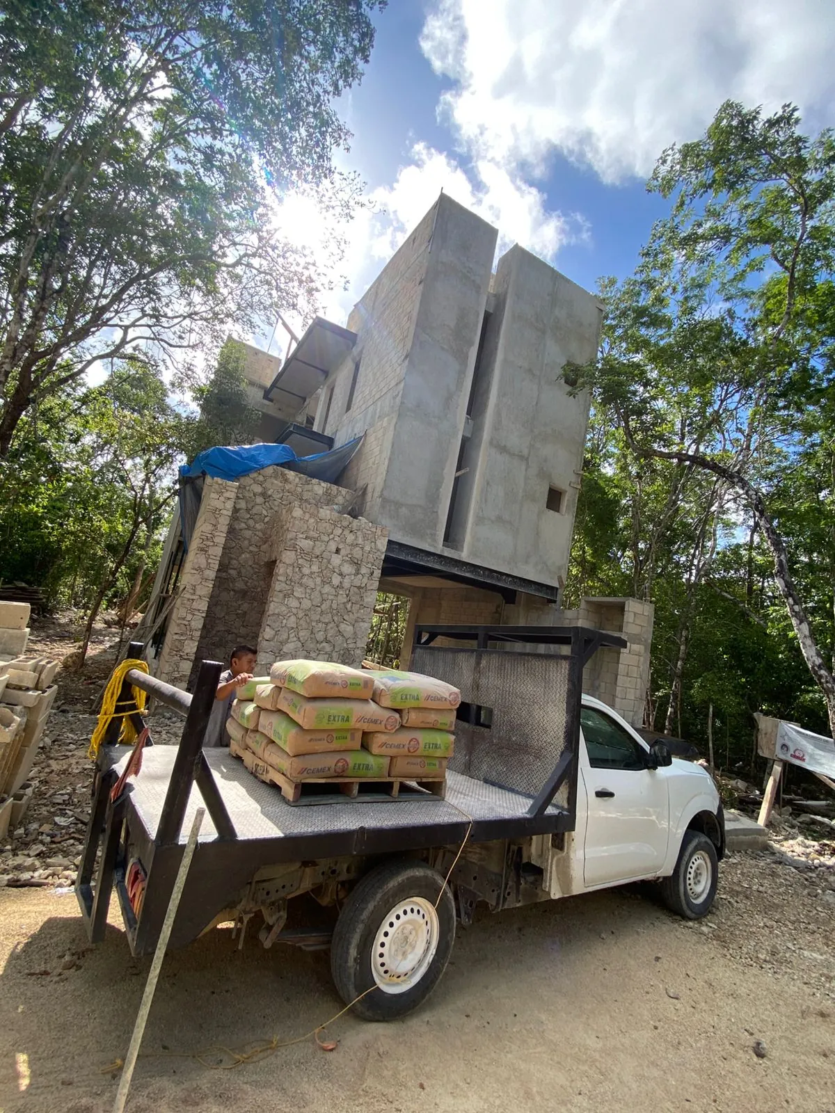 Camioneta con una tarima de sacos frente a una construcción de concreto